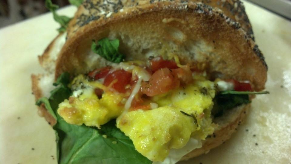Breakfast bagel with scrambled eggs and spinach with tomato